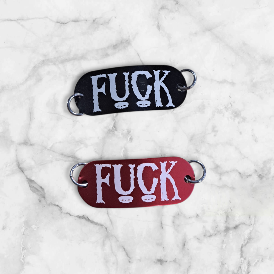 Bent aluminum lacing tag with Fuck engraved on it. Available in Black or Red
