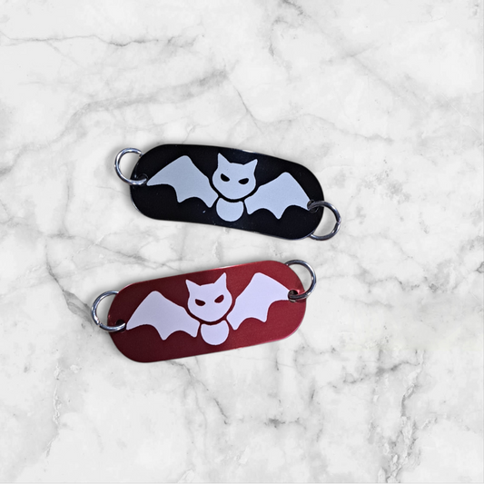 Bent aluminum lacing tag with a Bat engraved on it. Available in Black or Red