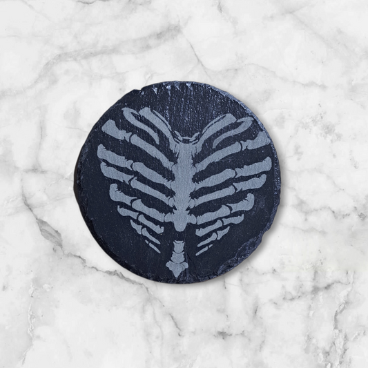 Round slate coaster with bone heart design engraved on it