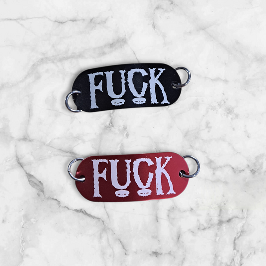 Bent aluminum lacing tag with Fuck engraved on it. Available in Black or Red