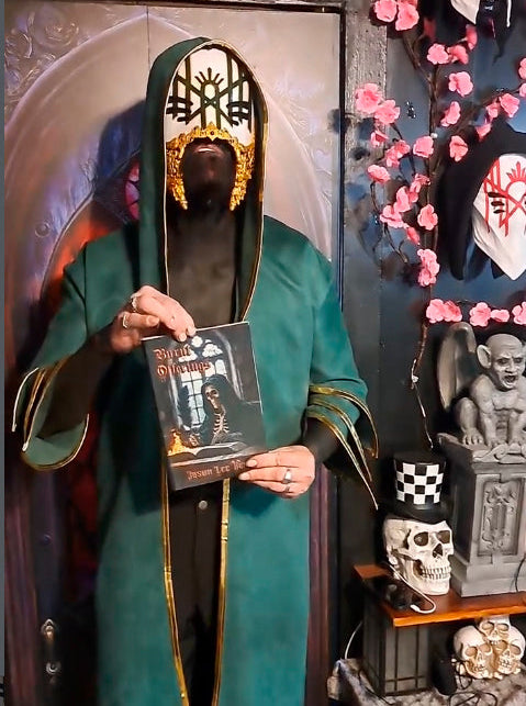 Vessel cosplayer holding a book with a decorative cover, standing in front of a shrine with skulls and flowers.