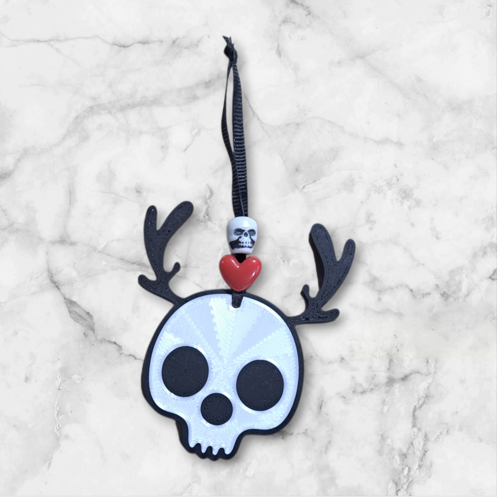Skull-shaped ornament with antlers beaded with a heart and skull ribbon hanger